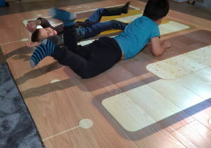 Chłopcy turlają się podczas zabaw z podłogą interaktywną.